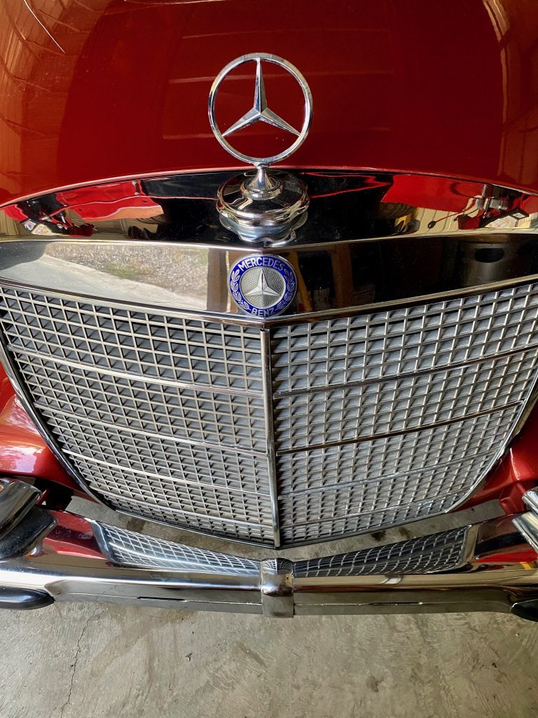 Red vintage Mercedes-Benz front grille close-up.