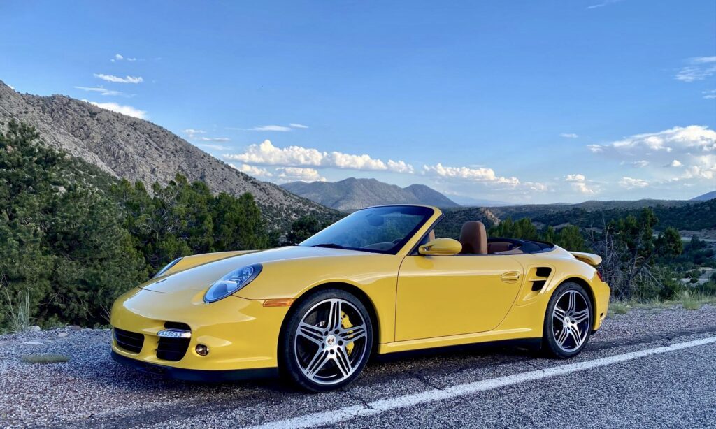 Yellow convertible sports car on mountain road.