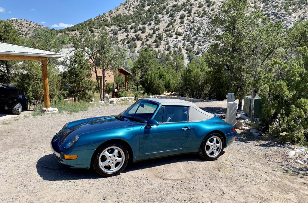 Blue convertible car parked in mountainous area.