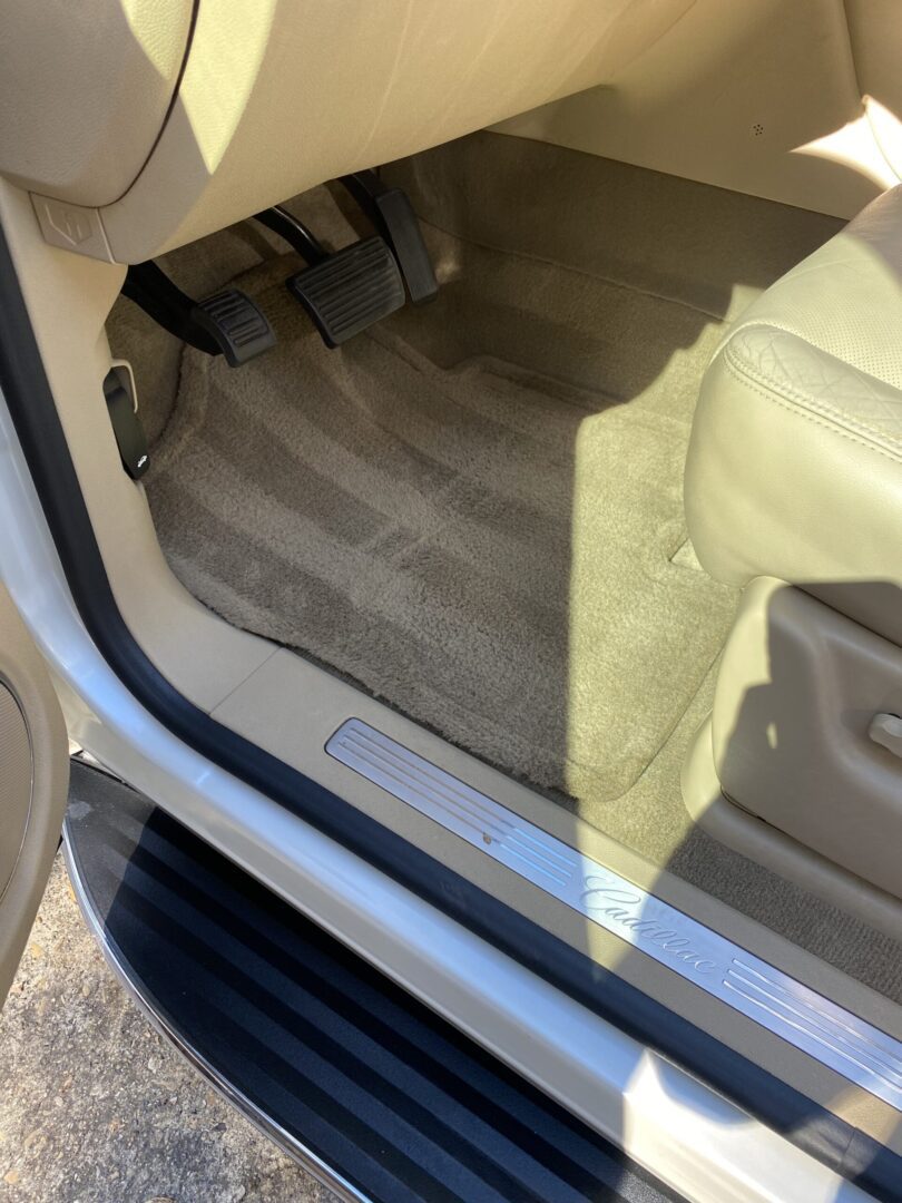 Car interior with pedals and floor mat.
