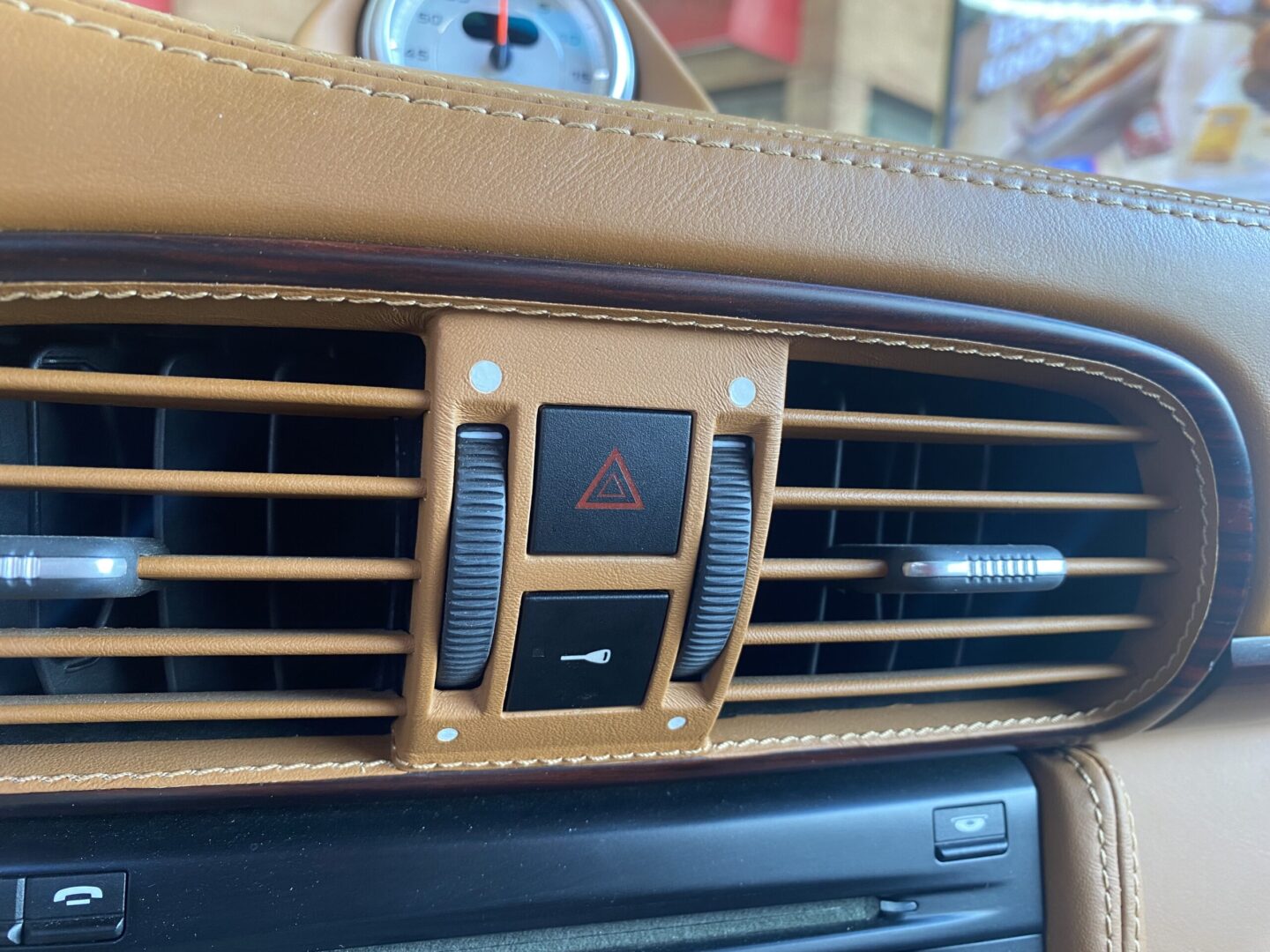 Car dashboard air vent with hazard button.