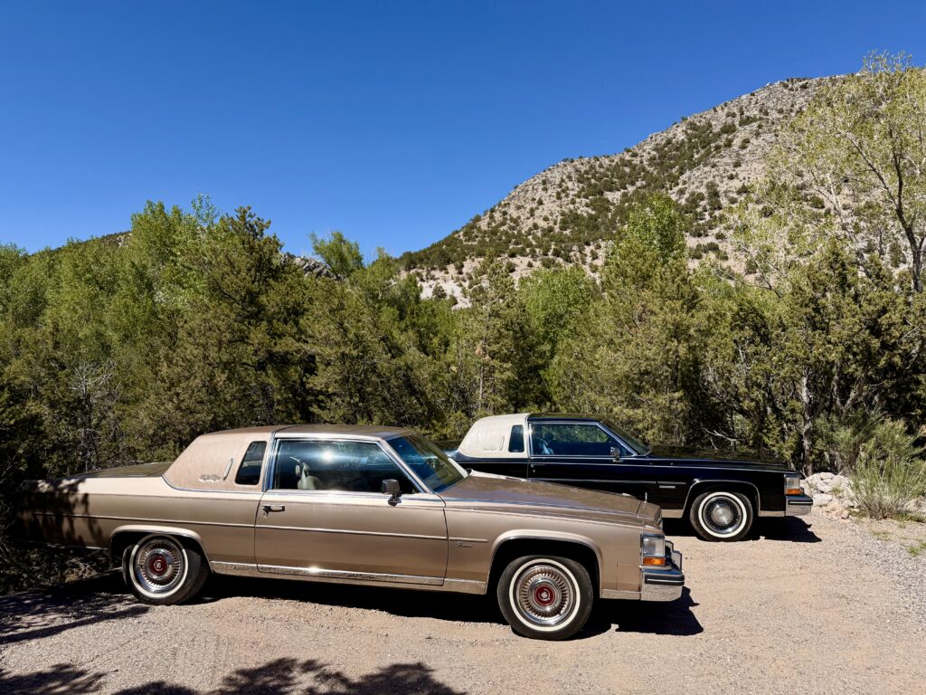 Two vintage cars parked near a mountain.