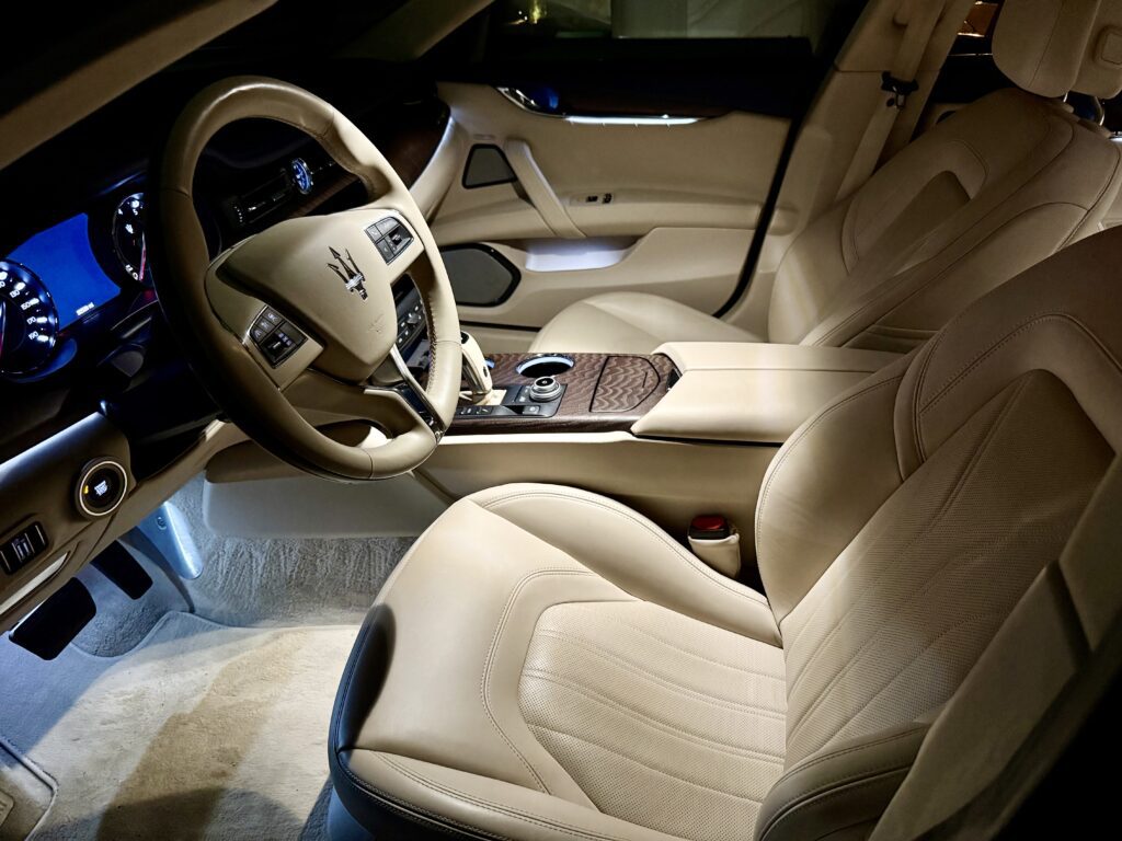 Luxury car interior with beige leather seats.
