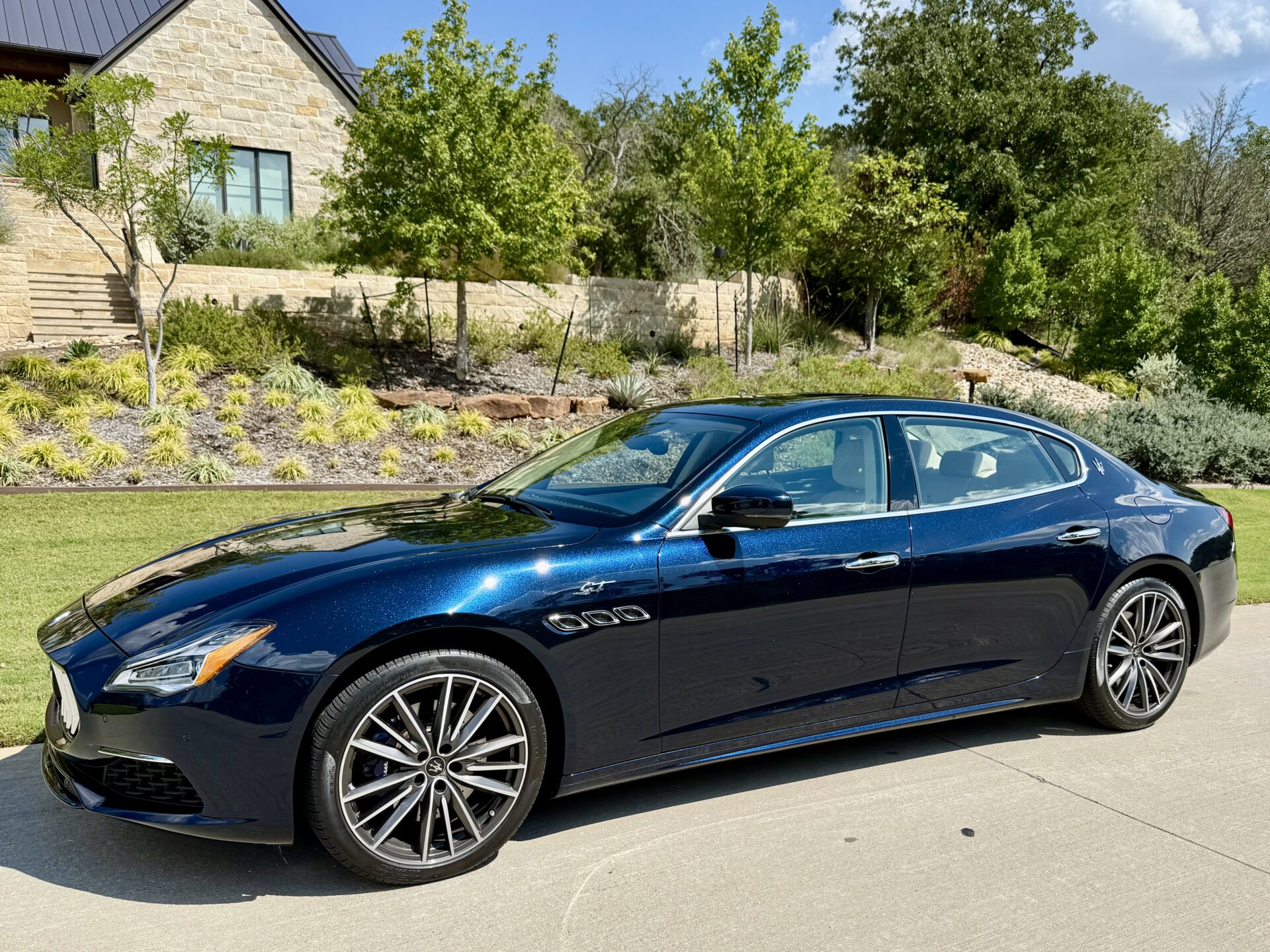 Blue luxury car parked near a house.