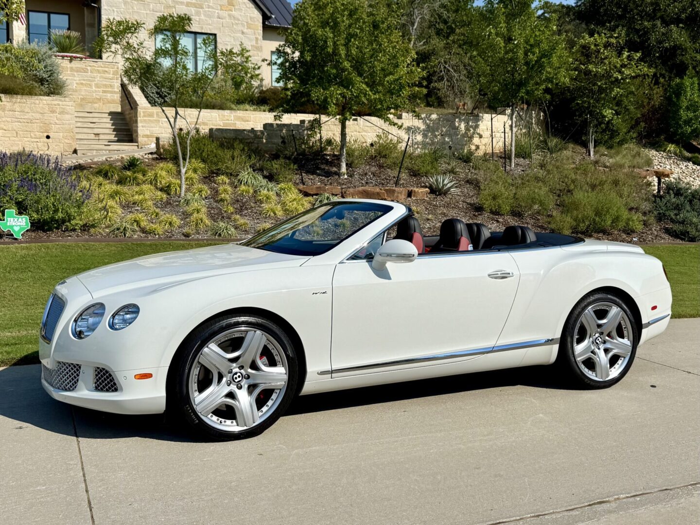 White convertible parked on sunny driveway.