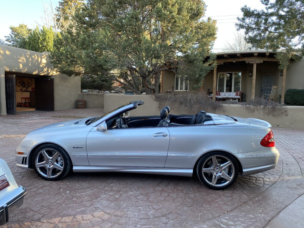 Silver convertible parked in a driveway.